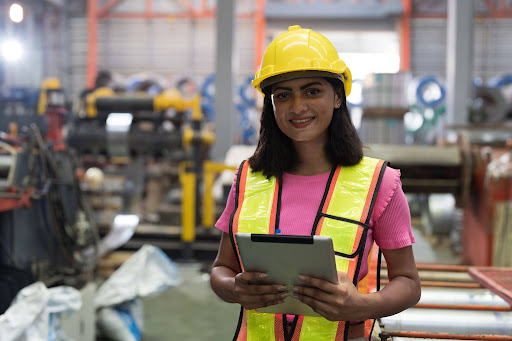 Woman with yellow hardhat, high visibility vest, and clipboard