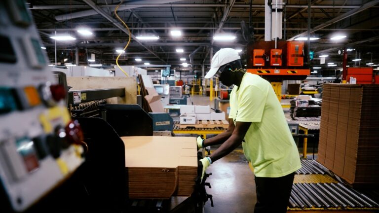 Manufacturing warehouse worker preparing cardboard, illustrating the challenge of managing multiple staffing agencies in production